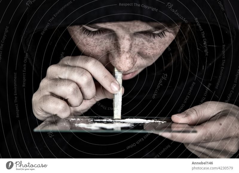 Drug Addict sniffing und snorting Kokain, Geschwindigkeit, Heroin oder andere Droge mit Geld aufgerollt auf Spiegel mit dunklem Hintergrund, Sucht, Drogen, deprimiert Konzept