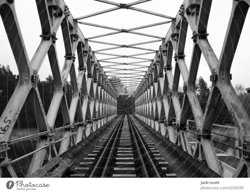 Brücke mit aufgelösten Tragwerksstrukturen in Grautönen Fachwerkbrücke Architektur Himmel Eisenbahnstrecke Eisenbahnbrücke Gleise Verkehrswege lost places