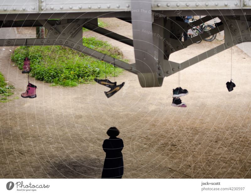Unter der Brücke, nicht den Boden unter den Schuhen verlieren. Shoefiti hängen lassen paarweise Straßenkunst unten Silhouette Mensch Prenzlauer Berg Berlin