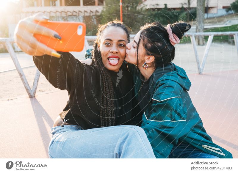 Multirassisches lesbisches Paar, das sich küsst, während es ein Selfie mit dem Smartphone im Freien macht gleichgeschlechtlich Kuss ausspannen Liebe Gedächtnis