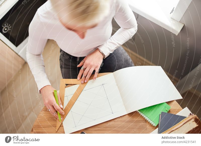 Crop Astrologe Zeichnung auf Papier am Schreibtisch im Haus zeichnen Dreieck Geometrie vorbereiten Astrologie Frau heimwärts Pseudowissenschaft göttlich