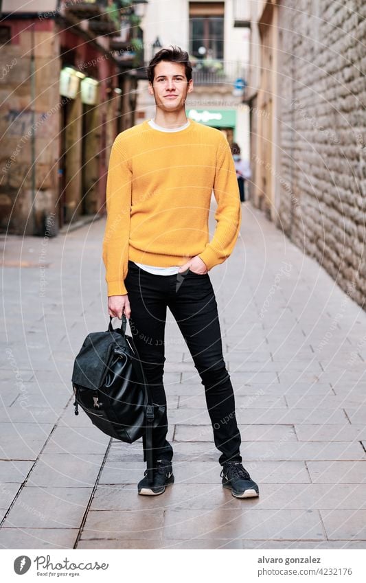 Porträt eines jungen Mannes, der im Freien auf der Straße steht. urban Großstadt Selbstvertrauen Rucksack Stehen posierend stylisch Beteiligung Schüler Blick