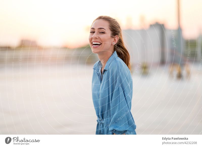 Porträt einer jungen Frau auf einem Dach, die den Sonnenuntergang genießt selbstbewusst Lächeln attraktiv schön junger Erwachsener Freude positiv Inhalt Stehen
