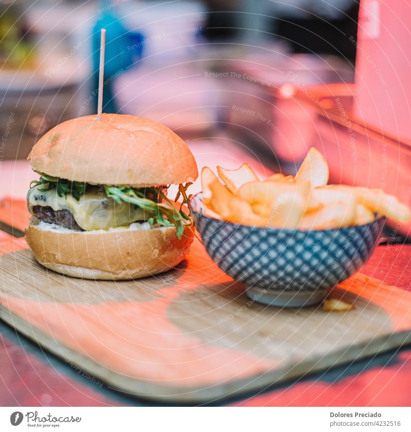 Gourmet-Burger mit Cheddar-Käse und Speck, begleitet von Deluxe-Pommes auf einem Holzbrett Ketchup isoliert Rindfleisch Holzplatte Tisch Cholesterin