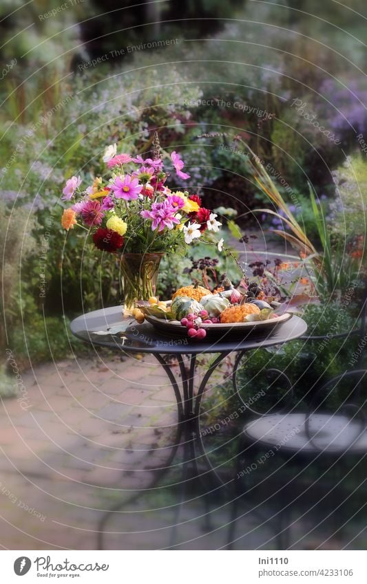 Zierkürbisse in flacher Schale und ein Blumenstrauß in Glasvase stehen auf kleinem Metalltisch draußen auf der Terrasse Herbst Garten Dahlien Cosmea Zieräpfel