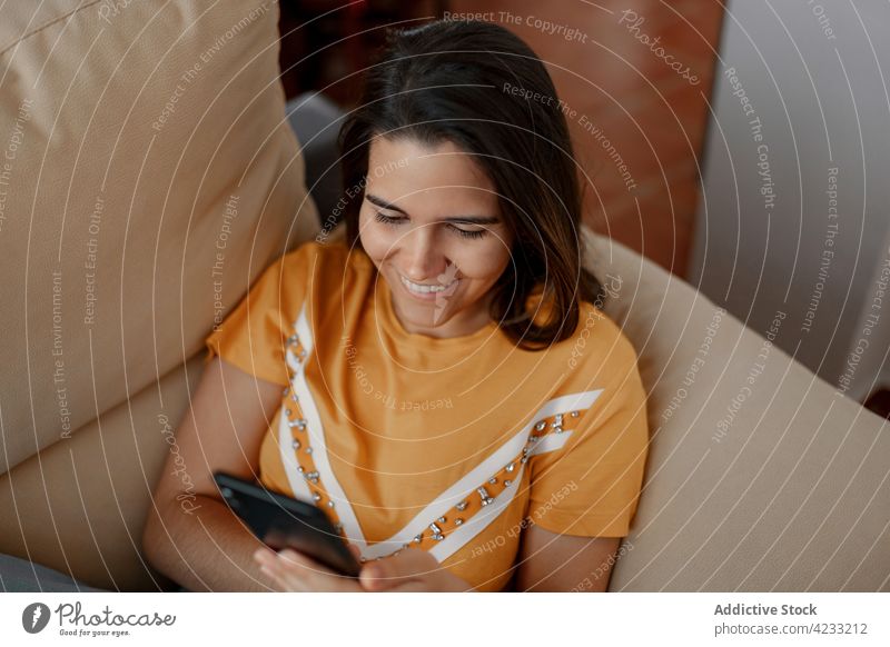 Frau, die zu Hause auf dem Sofa mit ihrem Smartphone chattet plaudernd Internet benutzend Apparatur Gerät Lächeln Lifestyle liegend Funktelefon Glück