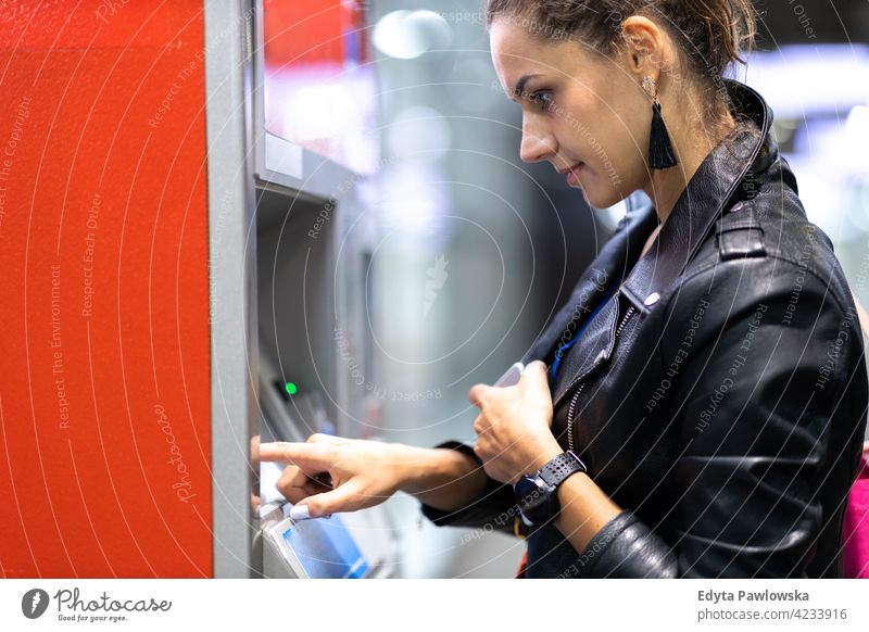 Junge Frau, die an einem Geldautomaten Geld abhebt zurückziehen atm Maschine Bank Banking Finanzen Bargeld Kreditkarte urban Straße Großstadt aktiv Menschen