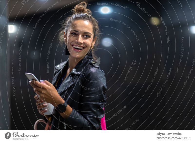 Junge Frau mit Smartphone bei Nacht in einer städtischen Umgebung urban Straße Großstadt aktiv Menschen junger Erwachsener lässig attraktiv Glück Kaukasier