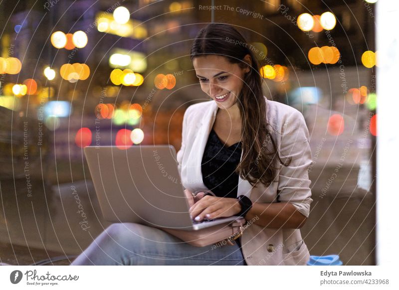 Junge Frau arbeitet an ihrem Laptop in der Stadt bei Nacht urban Straße Großstadt aktiv Menschen junger Erwachsener lässig attraktiv Glück Kaukasier genießend