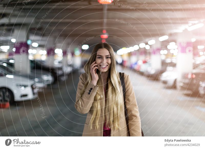 Frau mit Smartphone in Tiefgarage unterirdisch Garage parken Parkplatz PKW Autos Fahrzeug Verkehr Transport genießend Lifestyle jung Erwachsener Menschen