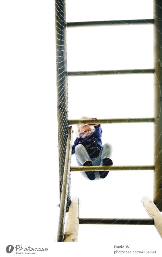 Kind klettert auf eine Klettergerüst Klettern Spielplatz mutig Mädchen Kindheit spielen Mut hoch klettergrüst draußen