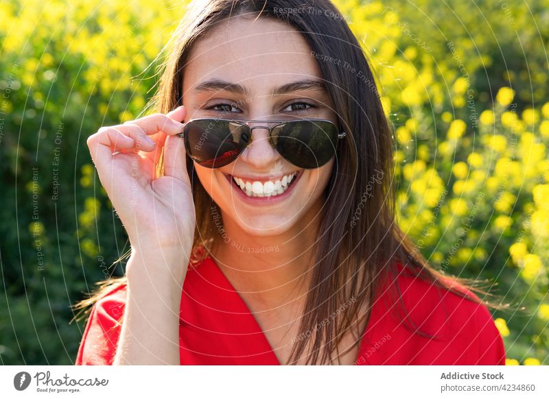Fröhliche Frau mit moderner Sonnenbrille in einem Feld auf dem Land Mode Stil heiter offen freundlich Art Landschaft Porträt herzlich Accessoire kreativ Design