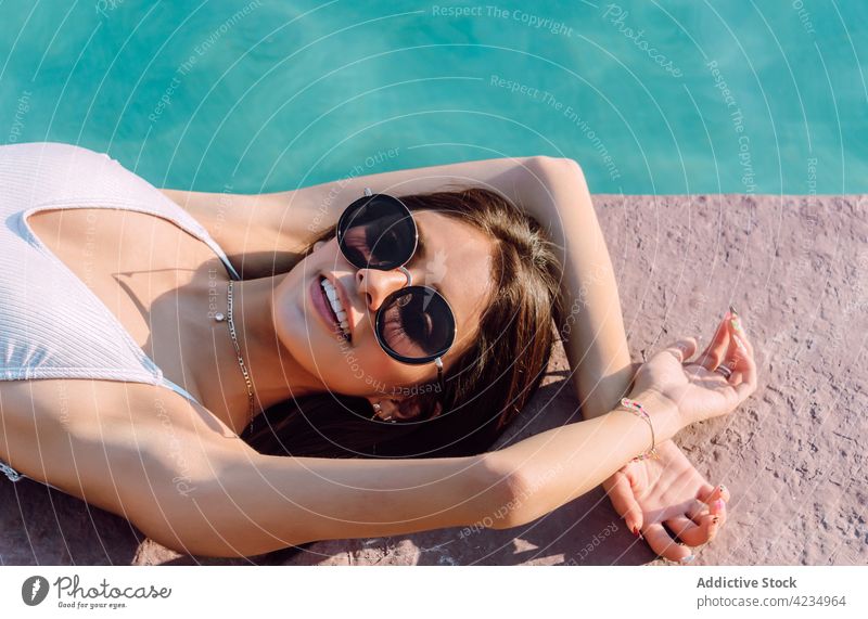 Sinnliche Touristin im Badeanzug, die sich am Swimmingpool ausruht Frau Lügen Pool Mode Stil sinnlich Sonnenbrille feminin Körper Urlaub reisen ruhen