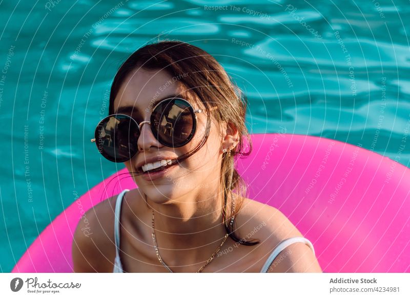 Inhalt Tourist im Badeanzug, der in einem Gummiring im Pool ruht Frau heiter Badebekleidung Sonnenbrille Urlaub feminin Reisender Angebot Glück ruhen Lächeln