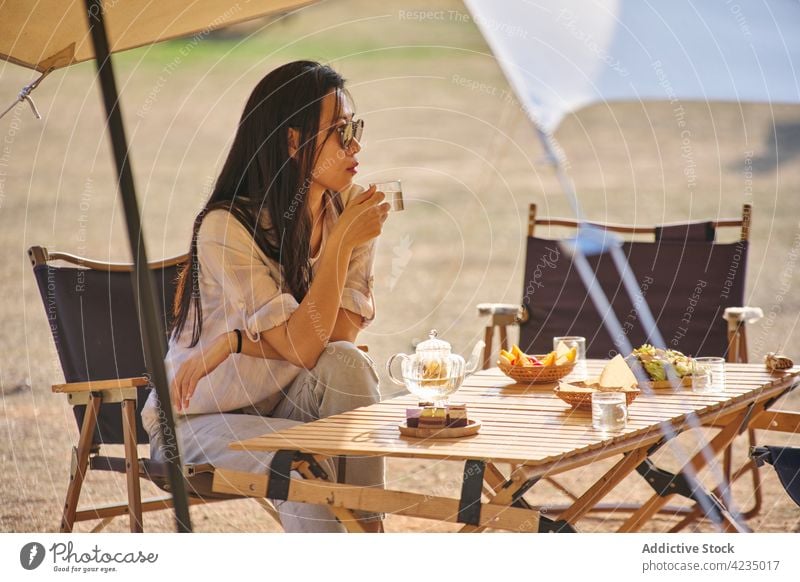 Asiatische Frau beim Entspannen auf dem Campingplatz Picknick Zelt Sommer ethnisch Sonnenbrille Model asiatisch Chinesisch eine Person genießen trinken