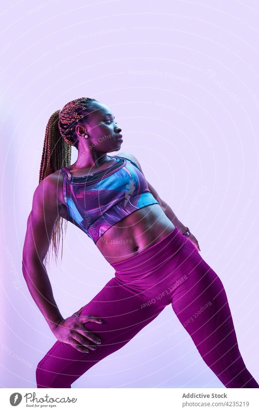 Fit schwarze Sportlerin in activewear auf blauem Hintergrund Athlet muskulös Körper Hand an der Hüfte selbstbewusst Stärke Bestimmen Sie Frau Porträt Kraft