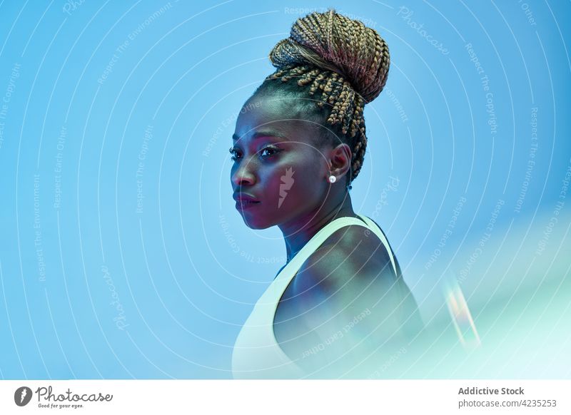 Konzentrierter schwarzer Sportler in Sportkleidung in Neonlicht Athlet Konzentration muskulös passen neonfarbig Afro-Look Frau Porträt Geflecht Achtsamkeit