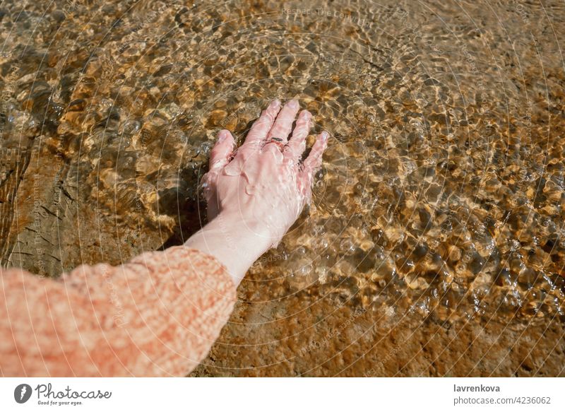 Hand der Frau im kalten Wasser auf einem Steg gesichtslos Strand Pier berührend Element Sauberkeit übersichtlich Pullover Rippeln Natur im Freien friedlich See
