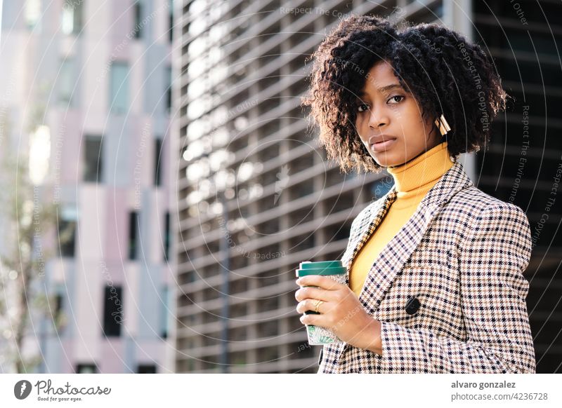 Geschäftsfrau hält eine Tasse Kaffee im Freien. Afro-Look Business Frau urban Großstadt finanziell Revier Straße Unternehmer Porträt professionell selbstbewusst