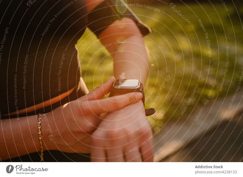 Crop-Sportlerin, die im Freien ihre Herzfrequenz auf einer Smartwatch misst prüfen intelligente Uhr bewerten Training Vitalität benutzend Apparatur Frau Gerät