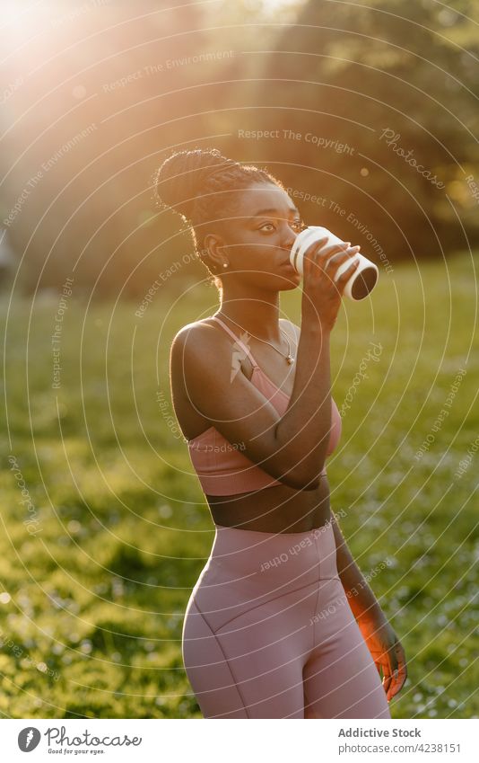 Schwarze Sportlerin mit Becher im Park Tasse trinken Athlet passen Sonnenuntergang Getränk Abend Frau ethnisch schwarz Afroamerikaner Training genießen
