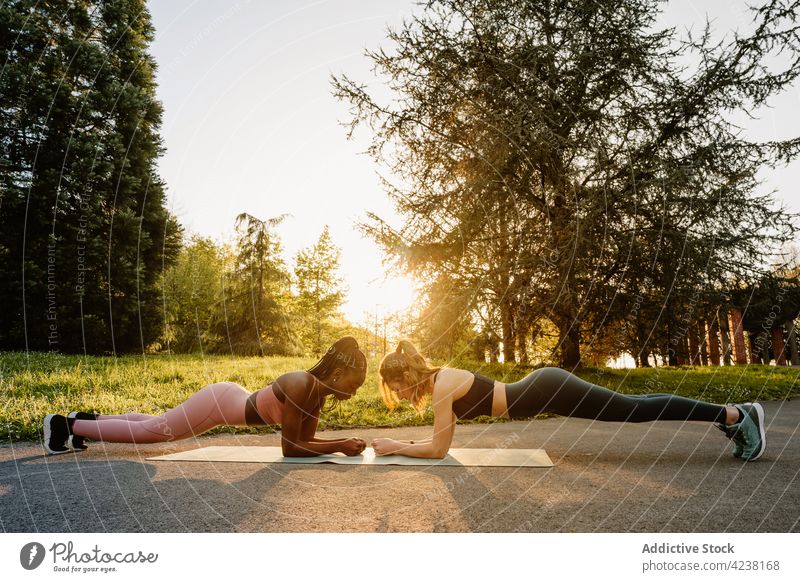 Fit weibliche Athleten tun plank Übung im Park Schiffsplanken Sportlerinnen Training Bauchmuskeln Unterleib Gleichgewicht schwarz Afroamerikaner