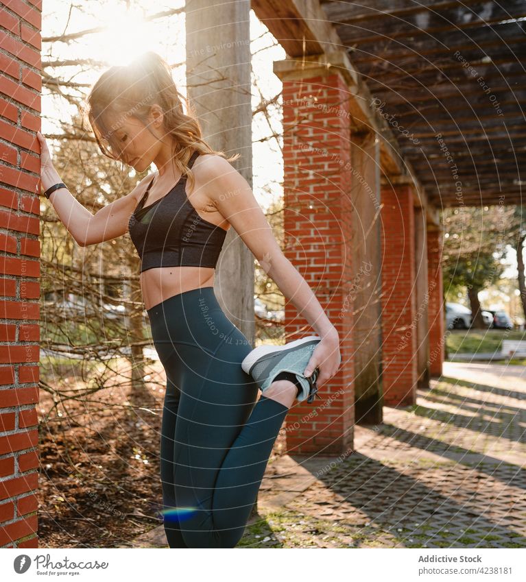 Sportlerin streckt ihr Bein beim Training in der Stadt Dehnung Bein angehoben Übung üben Sonnenschein Frau Turnschuh Wellness Gesunder Lebensstil Aufwärmen