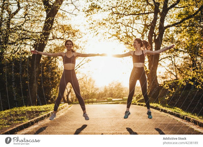 Schlanke Läuferinnen beim Aufwärmen im Park bei Sonnenuntergang Sportlerinnen Training passen Zusammensein Athlet Dehnung Arme Frau Frauen Fitness springen