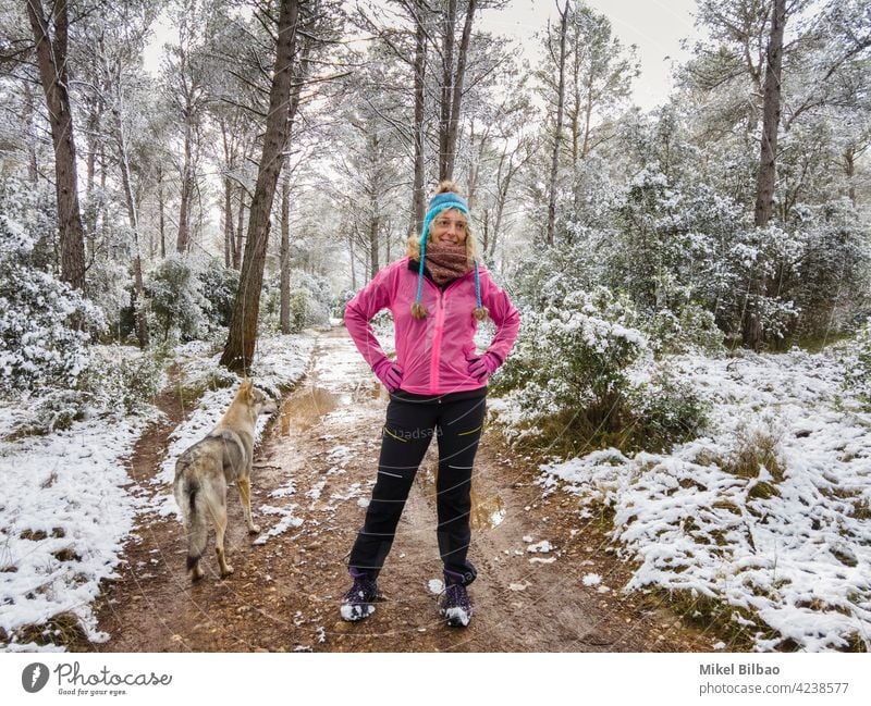 Kaukasische junge Frau mit einem Wolfshund genießt Schnee im Freien in einem Weg in einem Waldgebiet im Winter Zeit. Lifestyle Menschen Lebensstil genießen