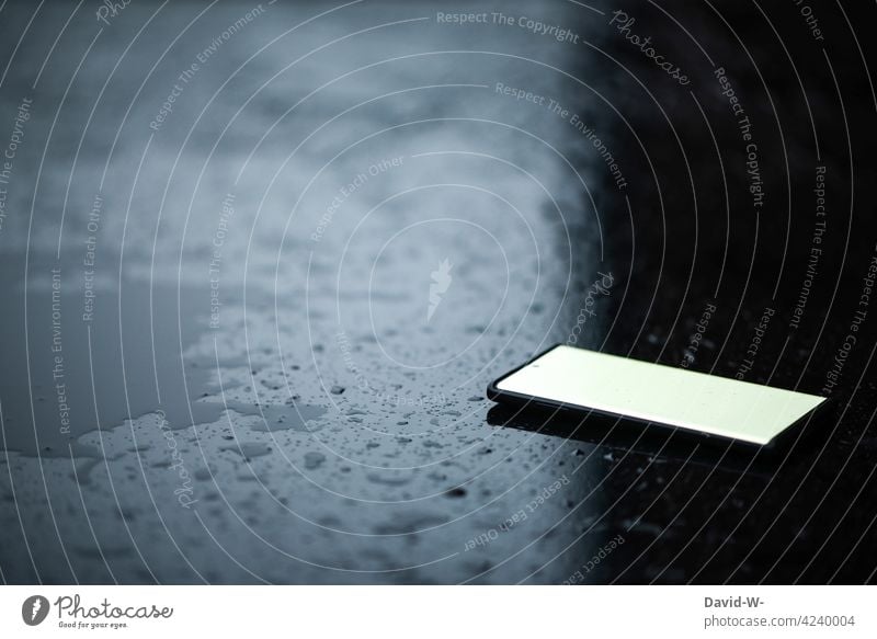 ein Handy liegt auf einem Tisch Smartphone liegen schlechtes Wetter Regenwetter nass Wassertropfen Mobile