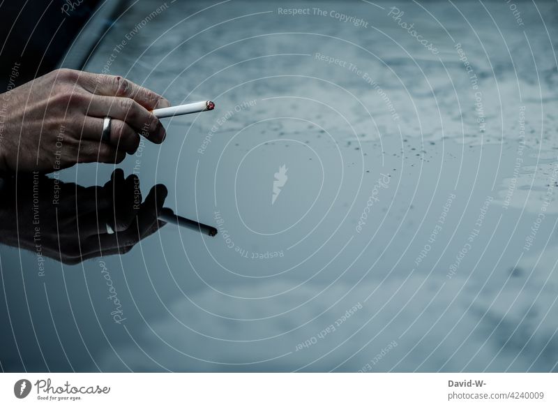 Hand hält eine Zigarette Raucher Sucht Suchtverhalten Abhängigkeit qualm Mann gesundheitsschädlich Spiegelung