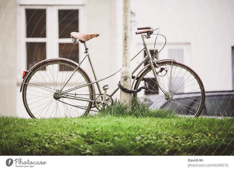 ein abgestelltes abgeschlossenes altes Fahrrad in einer Stadt nostalgisch Sicherheit fahrradschloss Laterne