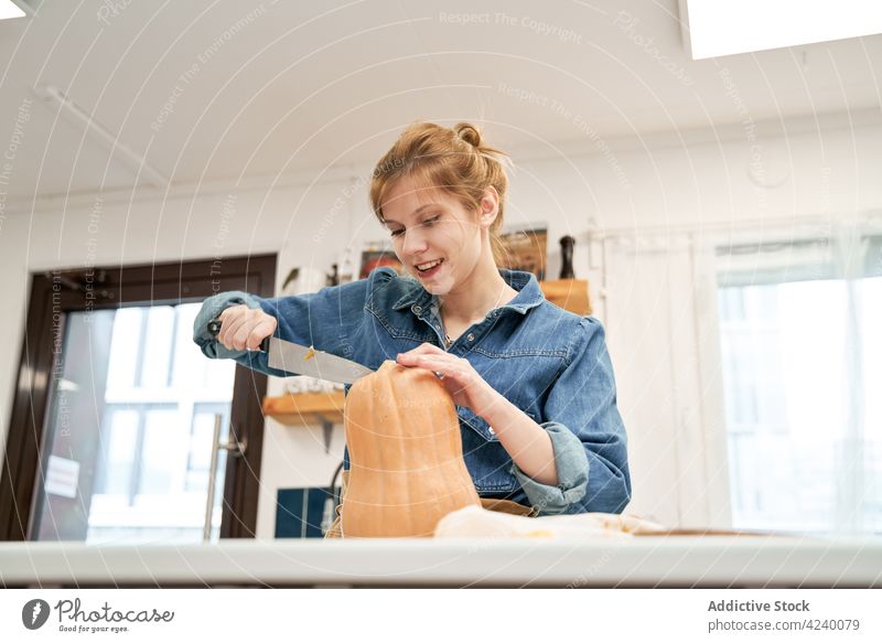 Frau schneidet frischen Kürbis am Tisch im Haus geschnitten Gemüse kulinarisch Rezept Messer Küche heimwärts Squash roh ganz Vegetarier Produkt natürlich