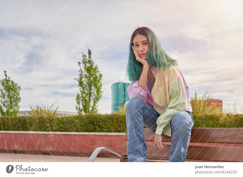 junges Mädchen mit türkisfarbenen Haaren sitzt auf einer Bank Behaarung Sitzen besinnlich Denken Ausdruck eine Person Emotion einsam sich[Akk] entspannen