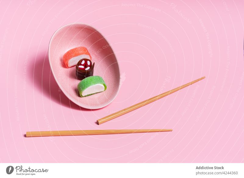 Leckeres Süßigkeiten-Sushi auf rosa Teller mit Stäbchen serviert süß Dessert Asiatische Küche Essstäbchen Mahlzeit Lebensmittel lecker Bonbon Tradition