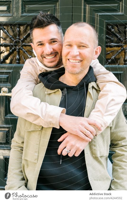 Glückliche junge multiethnische Schwule, die sich auf der Straße bei Tageslicht umarmen Paar Homosexualität Umarmen schwul Lächeln Liebe heiter Zusammensein