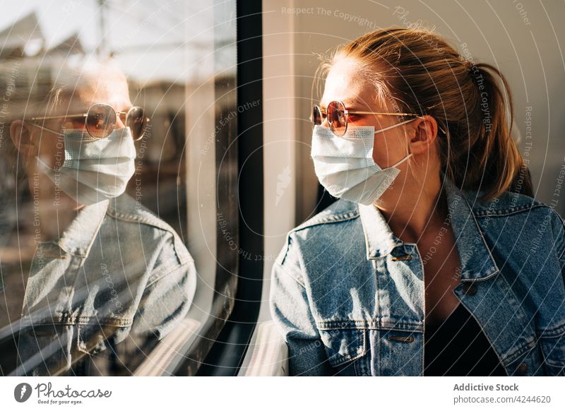 Frau mit Maske fährt im Zug Mundschutz Passagier Verkehr Arbeitsweg behüten Bund 19 COVID19 modern verhindern Mitfahrgelegenheit Fenster neue Normale