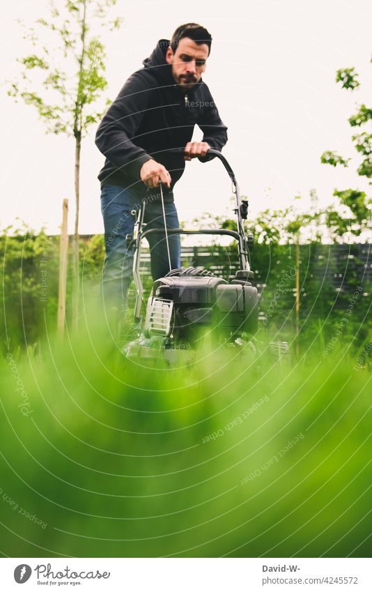 Mann startet den Rasenmäher mähen starten Gartenarbeit Pflege Gras grün rasenmähen Benzinrasenmäher