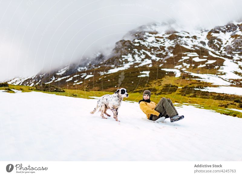Frau rutscht mit Hund einen verschneiten Hang hinunter Berge u. Gebirge Spaß Sliden Berghang Zusammensein laufen Lachen Tal Haustier Natur Schnee Tier Winter