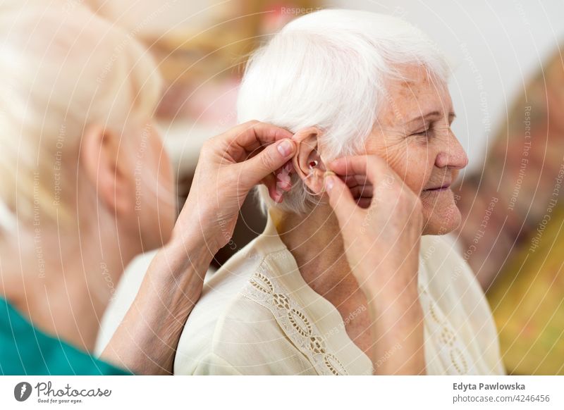 Krankenschwester setzt ein Hörgerät in das Ohr der Seniorin Gehörlosigkeit untersuchen hören Einstellung Audio Gerät abschließen Hand Audiologe anwendend