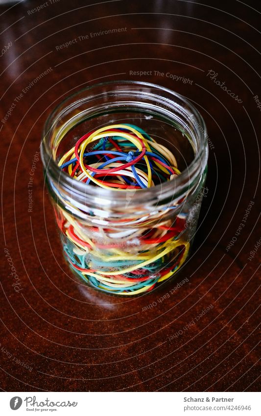 Gummibänder in einem Marmeladenglas sammeln Sammlung bunt Gummis befestigen gesammelt Einmachglas ringe Gummiringe Holztisch vielfältig Vielfalt verheddert