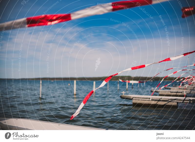 Vogelschutz | rot-weißes Flatterband ist am Anlegesteg für Boote befestigt und dient als Abschreckung für die Möwen Wind See Anleger Wasser Ufer Absperrband