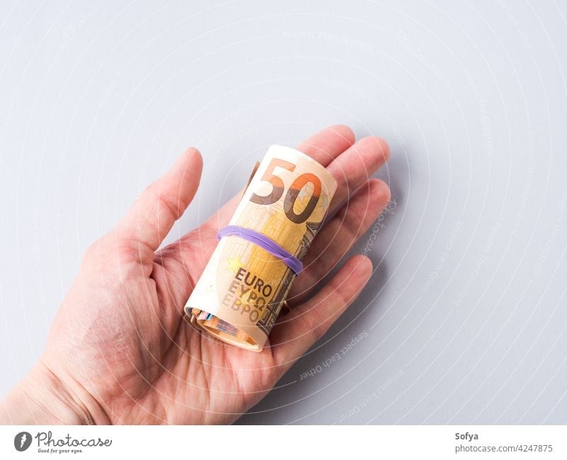 Euro 50 Wert Banknoten Rolle mit Gummi auf grauem Hintergrund rollen Geld Bargeld bezahlen 50 Euro Einsparungen Investition Hand Einkommen Kosten Wechseln