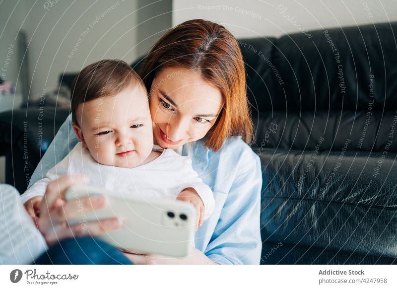 Selbstporträt von Mutter und Baby mit Mobiltelefon Frau Selbstportrait Selfie Smartphone Zusammensein Foto zu Hause Mobile Fotografie Gedächtnis modern Eltern