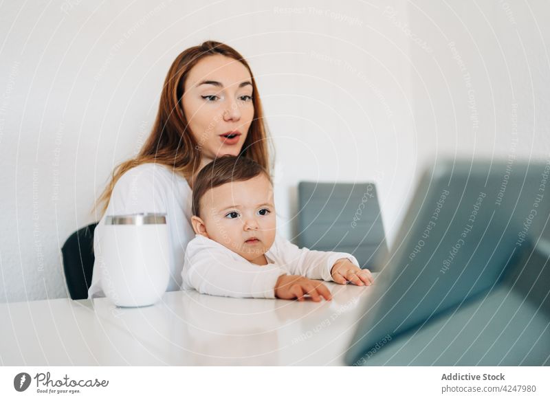 Mutter und Baby sehen sich ein Video auf einem Tablet an Tablette zuschauen Zusammensein achtsam unterhalten Interesse neugierig zu Hause Frau Mutterschaft jung