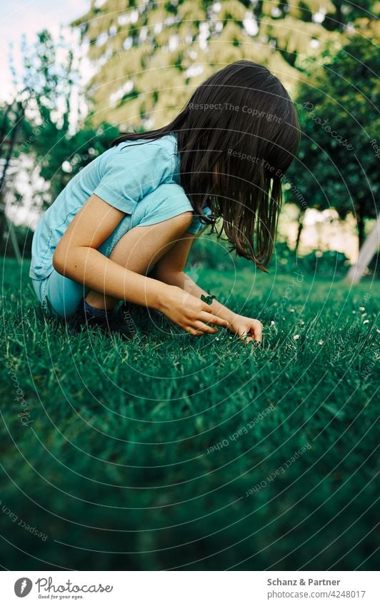 Kind hockt in im Garten und spielt spielen hocken blau türkis draußen suchen erforschen entdecken Außenaufnahme Sommer Freude Kindheit Natur Neugier Gras Wiese