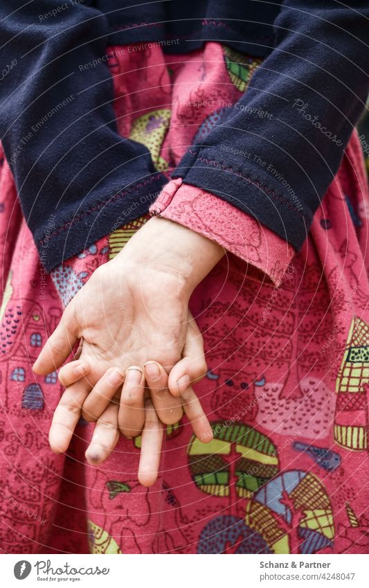 Mädchen hat Hände hinterm Rücken verhakt Kleid dreckige Fingernägel spielen Kindheit verlegen geduldig Geduld Muster rosa Hand Nahaufnahme Familienleben