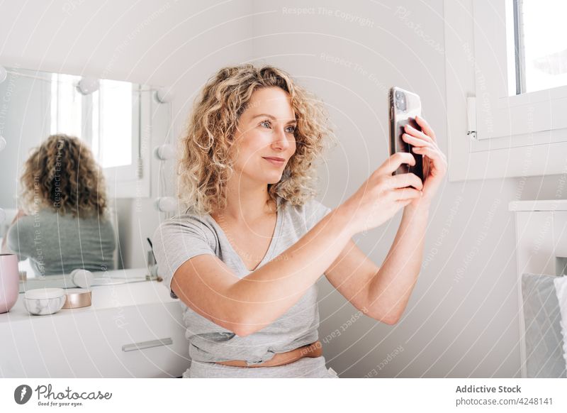 Lächelnde junge Frau, die ein Selfie im Badezimmer macht Smartphone positiv soziale Netzwerke fotografieren Freude Internet Blogger digital Mobile Telefon