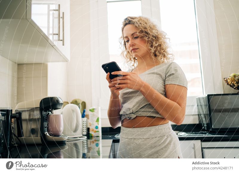 Ruhige Frau benutzt Smartphone in der Küche benutzend Browsen Windstille heimisch zu Hause Telefon Apparatur Funktelefon Gerät lässig Mobile Anschluss online