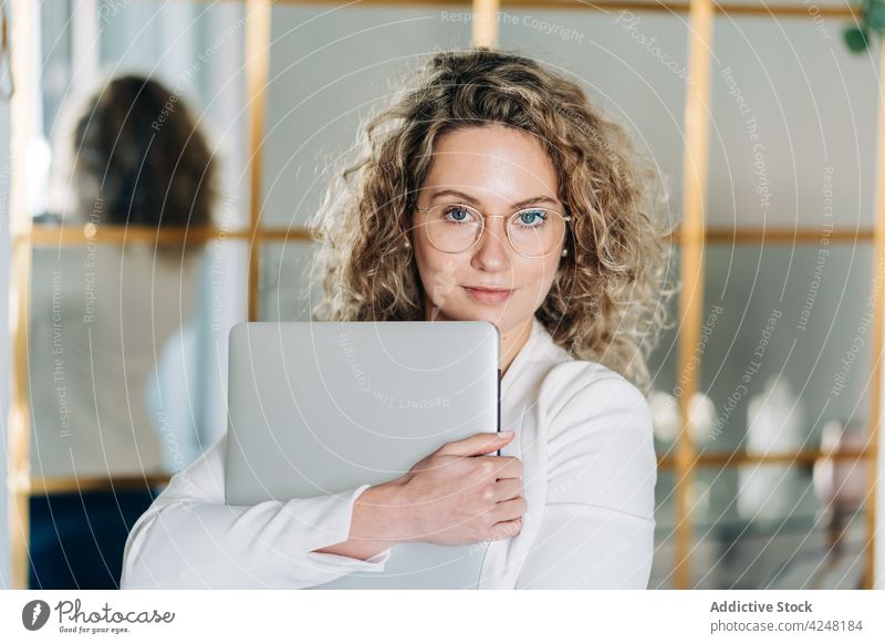 Stilvolle junge Mitarbeiterin mit Laptop in der Hand Frau selbständig elegant selbstbewusst Job Arbeit Arbeitsbereich Internet online Menschliches Gesicht